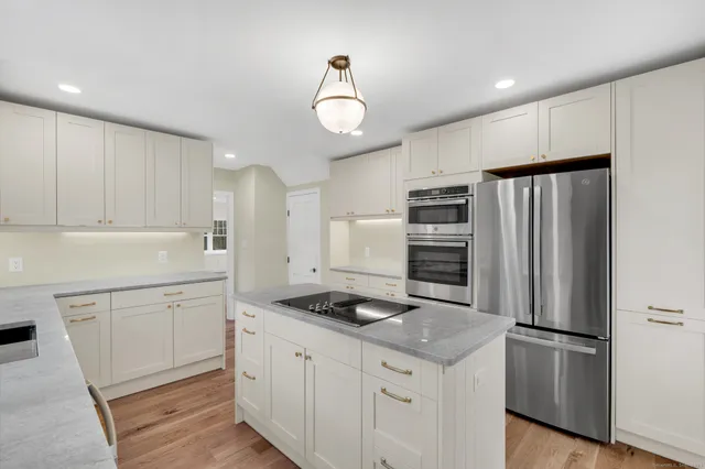 a kitchen with stainless steel appliances granite countertop a refrigerator and a stove top oven