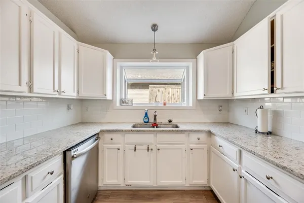 a kitchen with stainless steel appliances granite countertop white cabinets sink and dishwasher with wooden floor