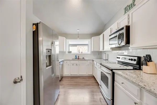 a kitchen with stainless steel appliances granite countertop a refrigerator and a stove top oven
