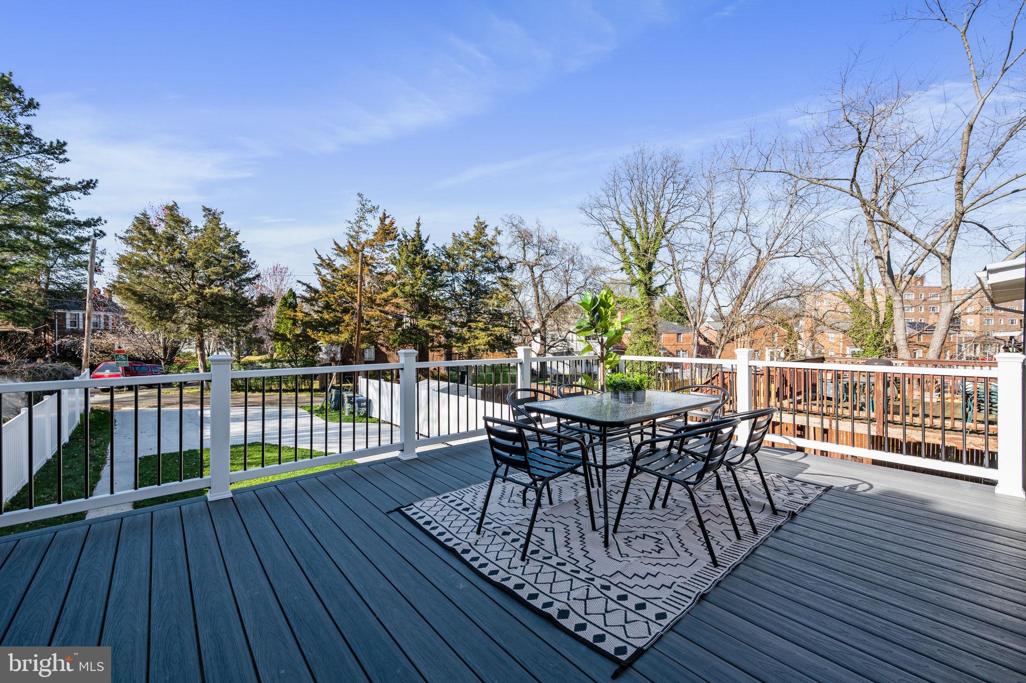 a view of a roof deck with table and chairs a barbeque with wooden floor and fence