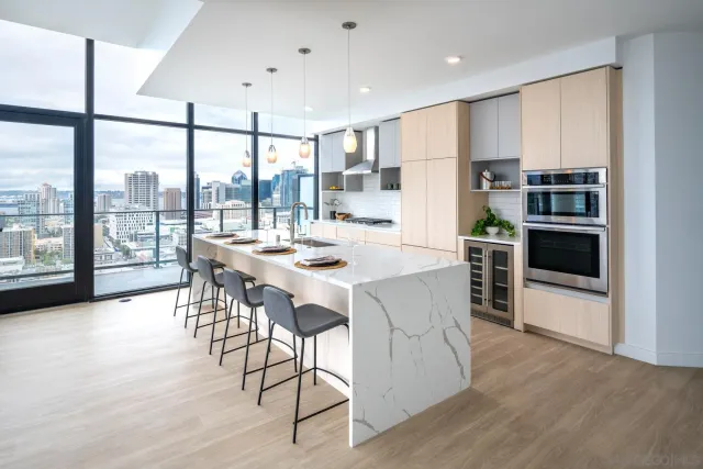 a kitchen with stainless steel appliances kitchen island granite countertop a stove a refrigerator a dining table and chairs with wooden floor