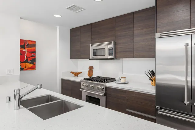 a kitchen with stainless steel appliances granite countertop a sink a stove and a refrigerator