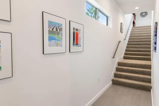 a view of staircase with lots of frames on wall and a window