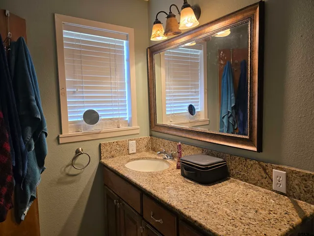 a bathroom with a granite countertop toilet sink and mirror
