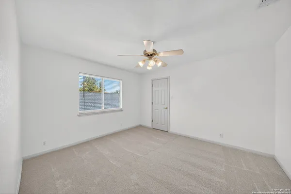 an empty room with windows and chandelier fan
