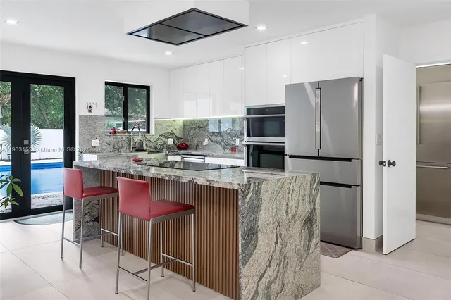 a kitchen with stainless steel appliances kitchen island granite countertop a refrigerator and a stove top oven