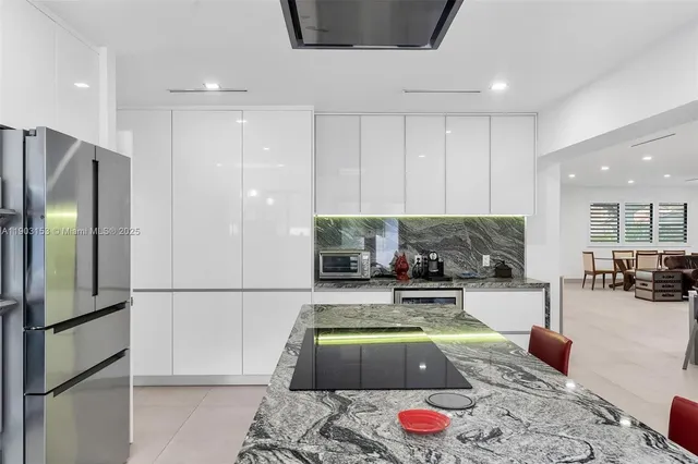 a living room with furniture a refrigerator and kitchen view