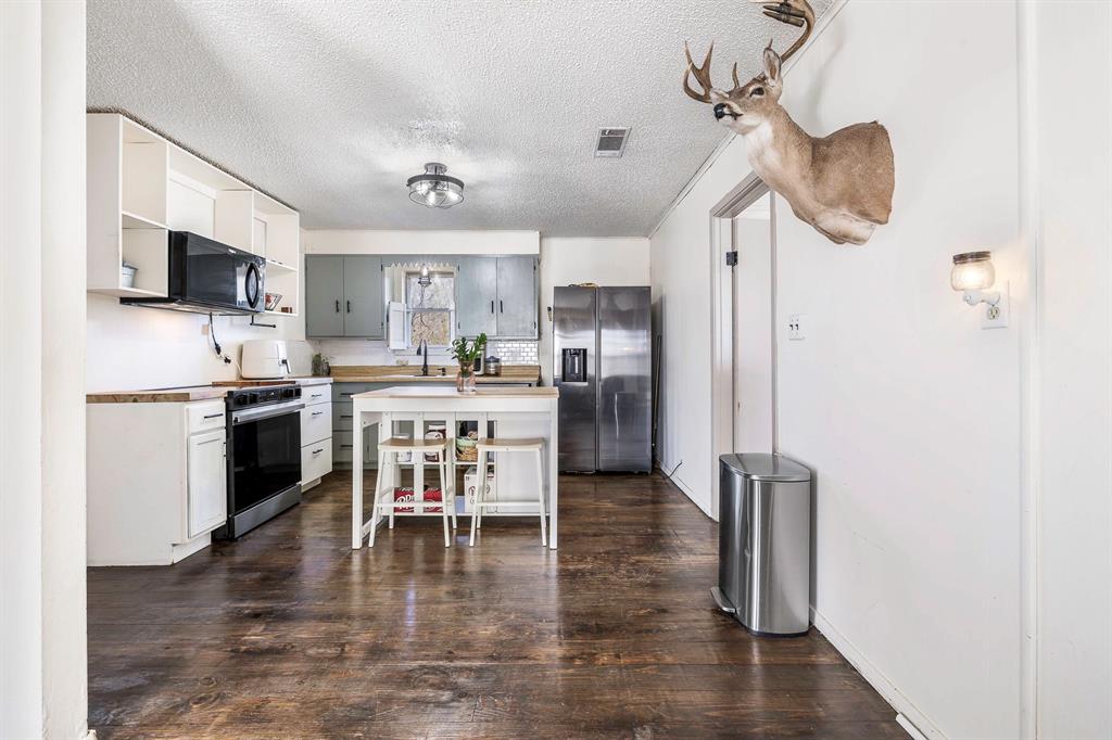 132 Maple Dublin, TX 76446 - Photo 6 of 27 a kitchen with stainless steel appliances granite countertop a refrigerator a stove top oven a sink dishwasher and white cabinets with wooden floor
