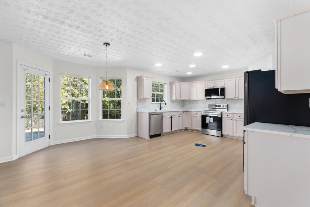3501 Bogan Mill Road Northeast Buford, GA 30519 - Photo 18 of 59 a large white kitchen with stainless steel appliances kitchen island granite countertop a refrigerator oven a sink dishwasher and white cabinets with wooden floor