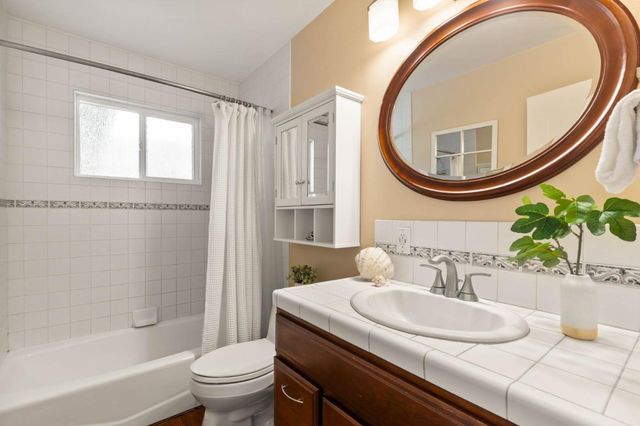 a bathroom with a sink a mirror a toilet and a window