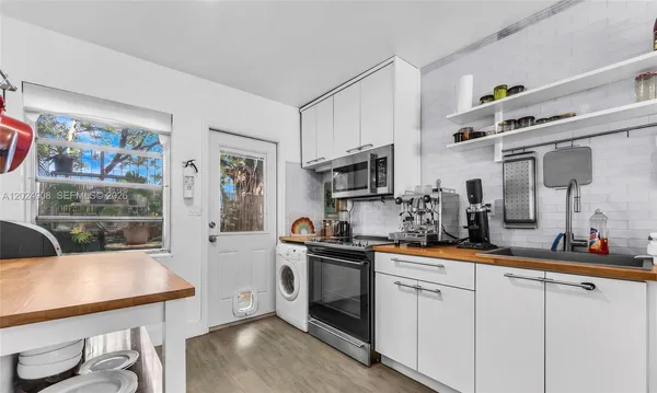 a kitchen with stainless steel appliances a sink a stove a refrigerator cabinets and a dining table
