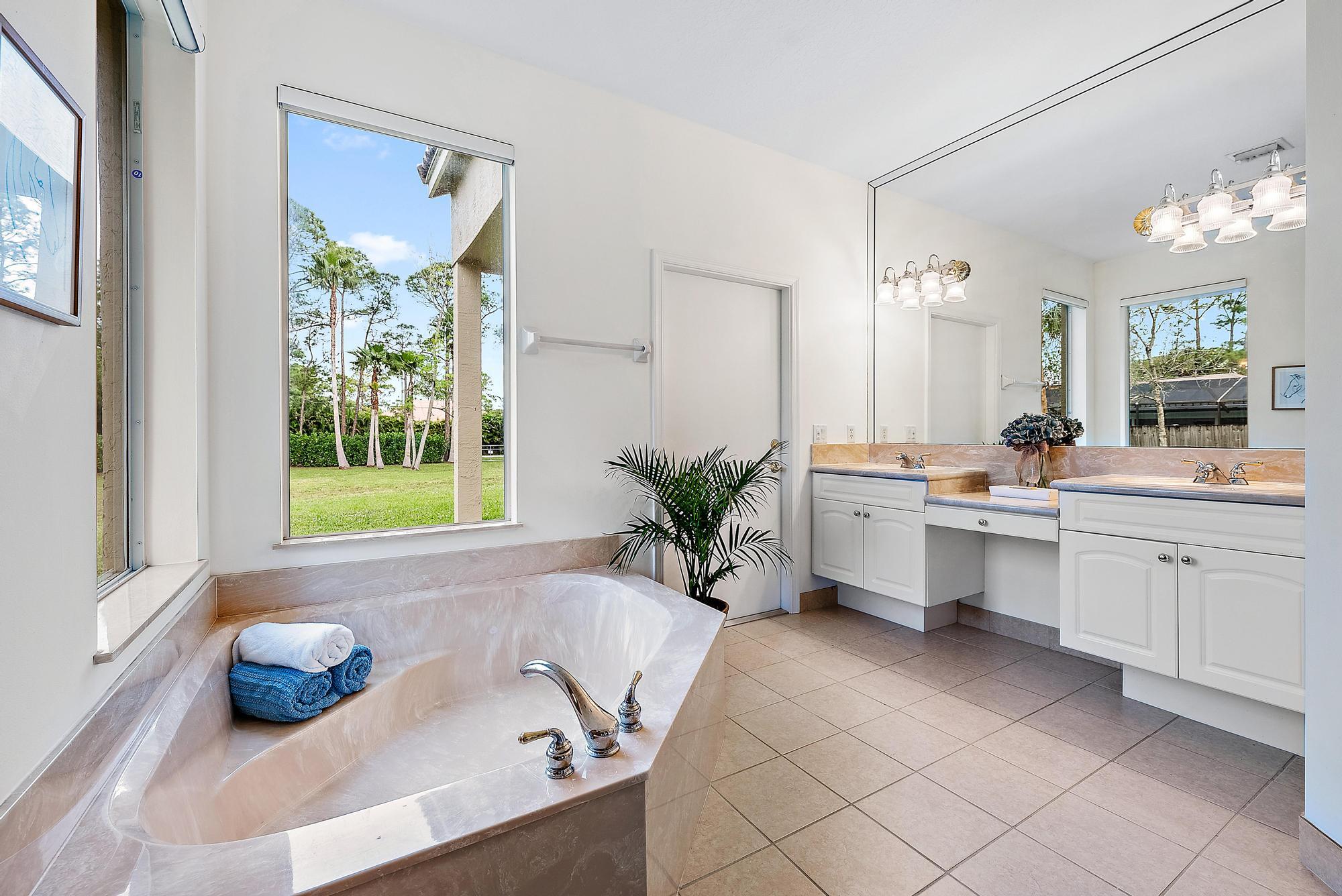 15644 Billy Goat Lane Jupiter, FL 33478 - Photo 19 of 39 a bathroom with a tub a sink and a window