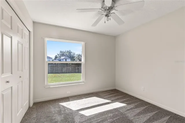 an empty room with windows and fan