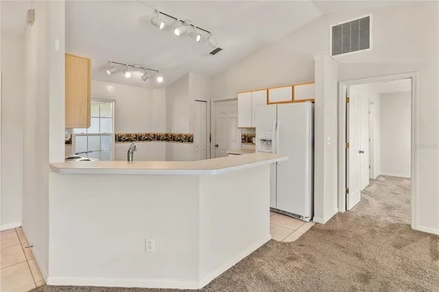 a room with kitchen island a white cabinets and refrigerator