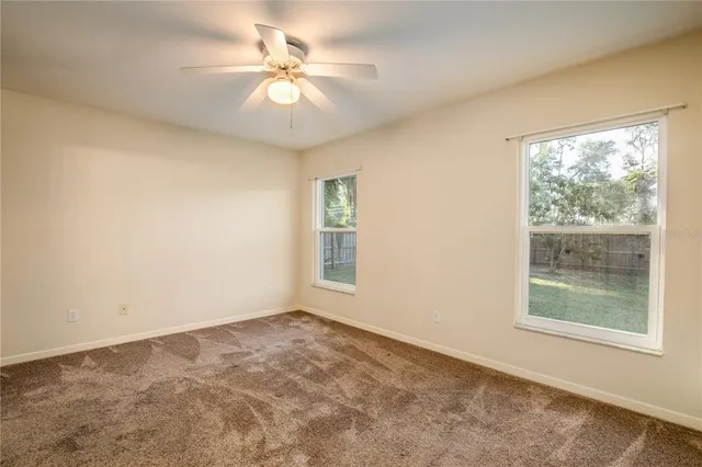 an empty room with windows and fan