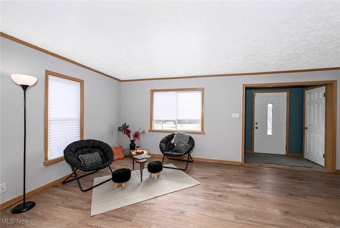 1164 Copley Road Akron, OH 44320 - Photo 17 of 50 Living area featuring a textured ceiling, baseboards, wood finished floors, and crown molding