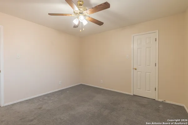 an empty room with a chandelier fan and windows