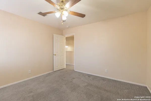 an empty room with a chandelier fan and a ceiling fan