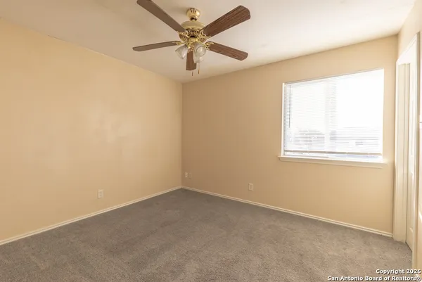 an empty room with a window and a fan