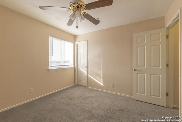 an empty room with windows and fan