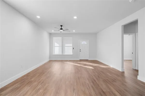 a view of an empty room with wooden floor and a window