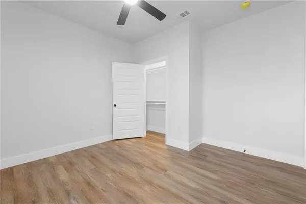an empty room with wooden floor and ceiling fan