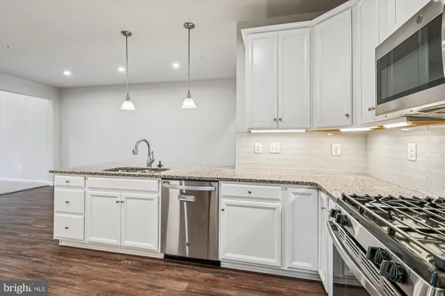 a kitchen with stainless steel appliances granite countertop a sink and a stove