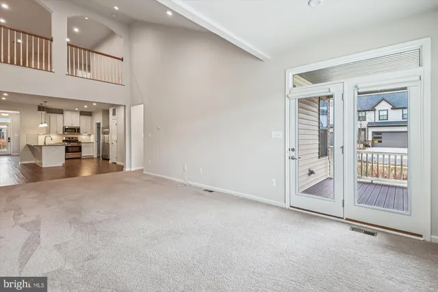 a view of an empty room and a kitchen