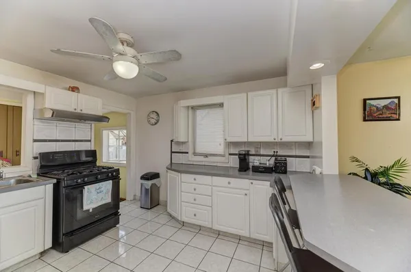 a kitchen with stainless steel appliances a stove a sink and white cabinets