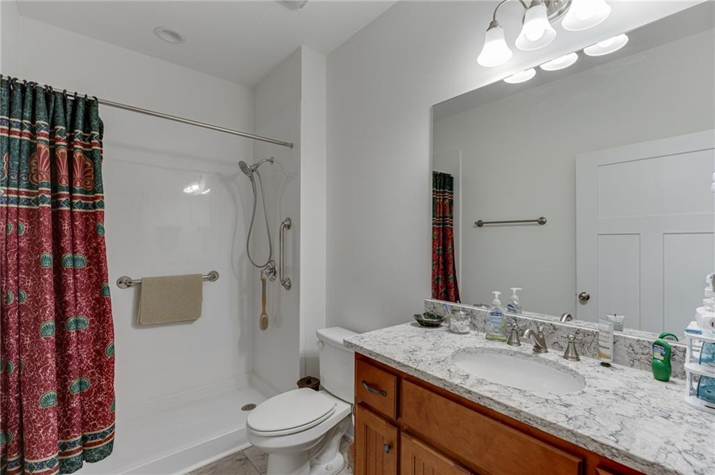7660 Fern Lane Lula, GA 30554 - Photo 29 of 50 a bathroom with a granite countertop sink toilet a mirror and shower