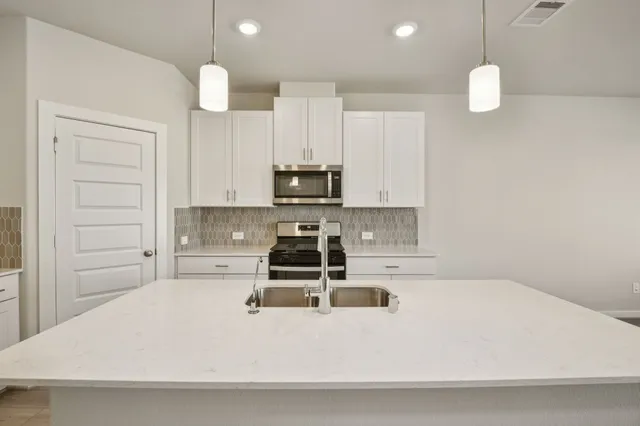 a kitchen with kitchen island a white counter top space stainless steel appliances and cabinets
