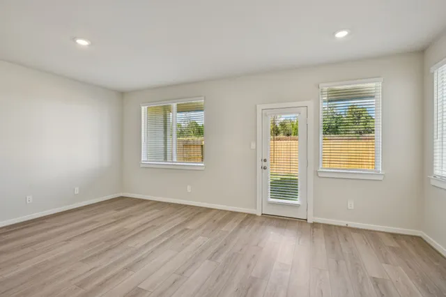 a view of an empty room with wooden floor and a window