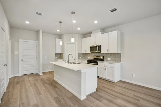 a kitchen with white cabinets appliances and sink