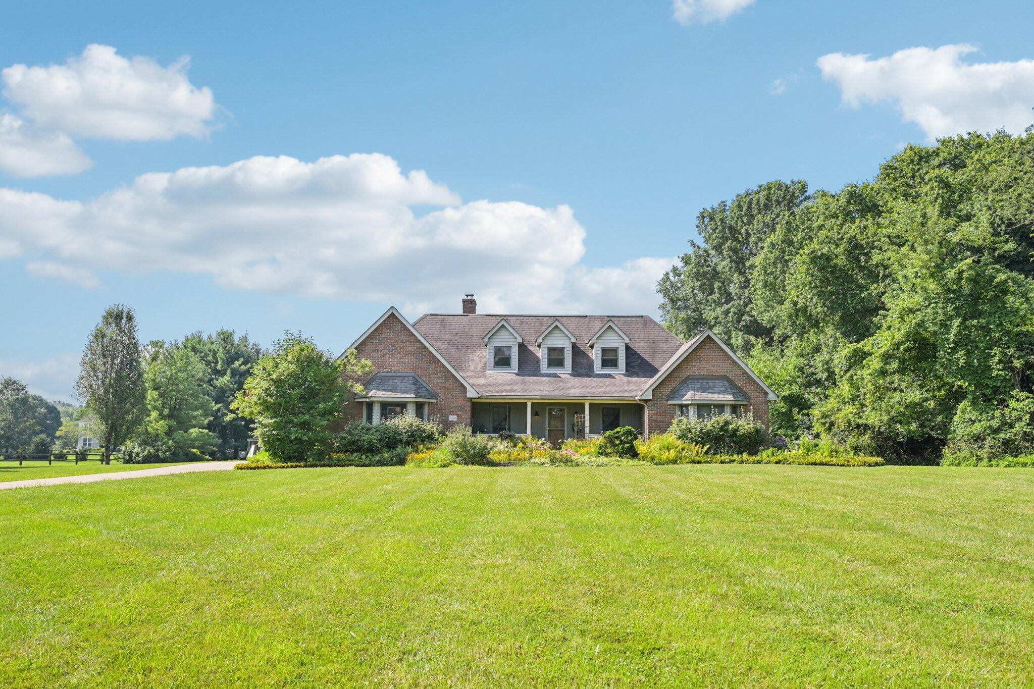 7700 Plumb Road Galena, OH 43021 - Photo 25 of 94 Charming front elevation with full-length covered porch, dormer windows, and colorful garden beds welcomes you home.