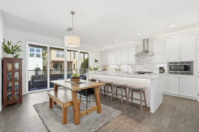 a kitchen with stainless steel appliances kitchen island granite countertop a table chairs and a refrigerator