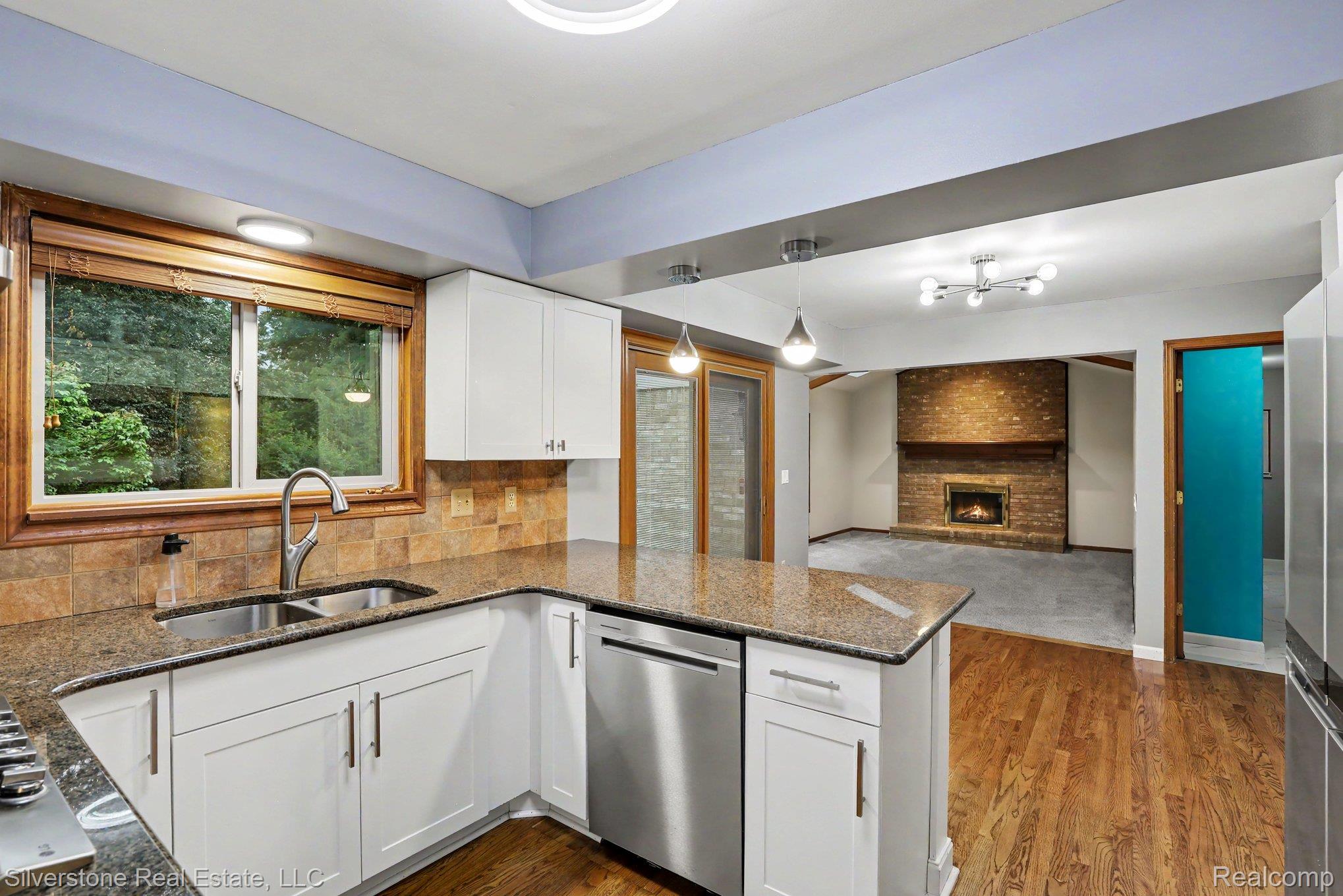 869 Timberline Drive Rochester, MI 48309 - Photo 6 of 29 Kitchen with granite countertops, stainless steel appliances, white cabinetry, and wood-finish flooring
