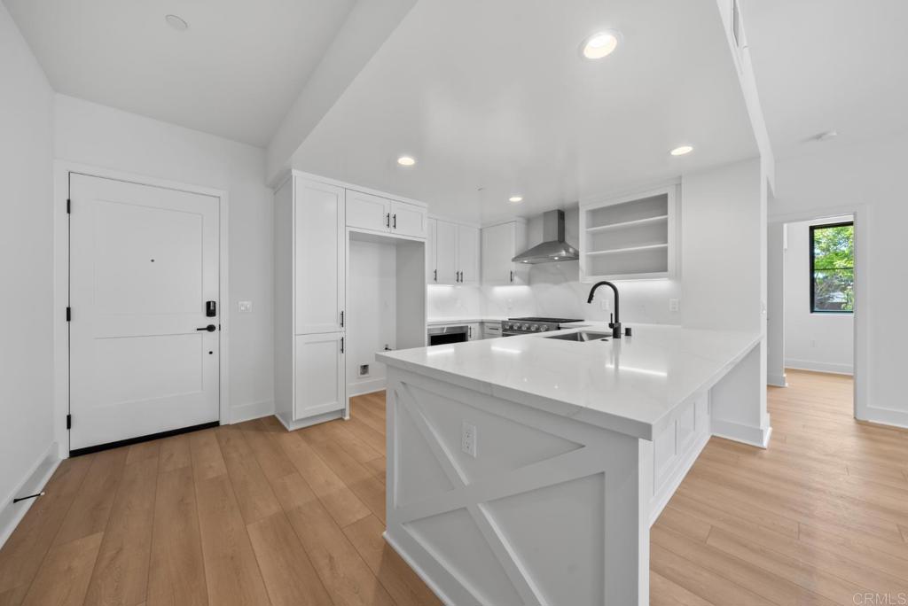 1101 Catania, Unit 104 Encinitas, CA 92024 - Photo 6 of 41 a large white kitchen with stainless steel appliances a sink dishwasher a stove and a refrigerator with wooden floor