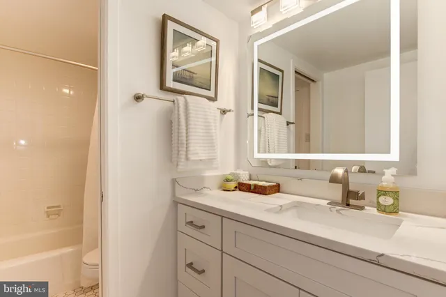 a living room with couches and kitchen view with wooden floor