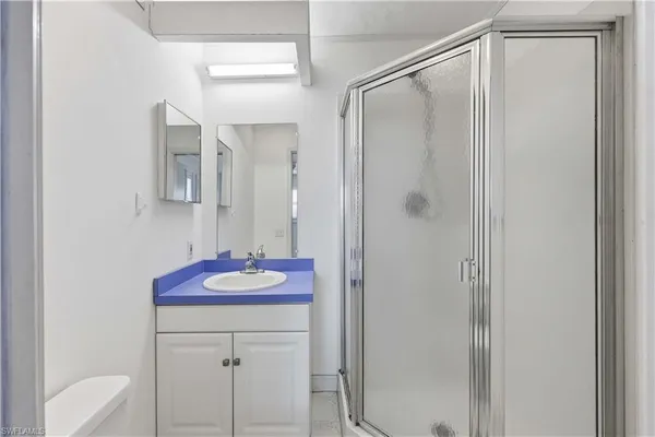 a bathroom with a granite countertop shower sink vanity and mirror