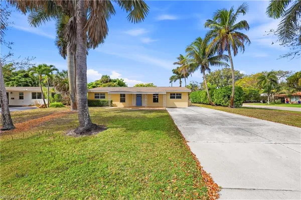 a front view of a house with a yard and palm trees