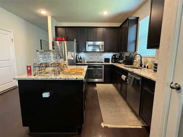 a kitchen with kitchen island granite countertop a sink stove and refrigerator