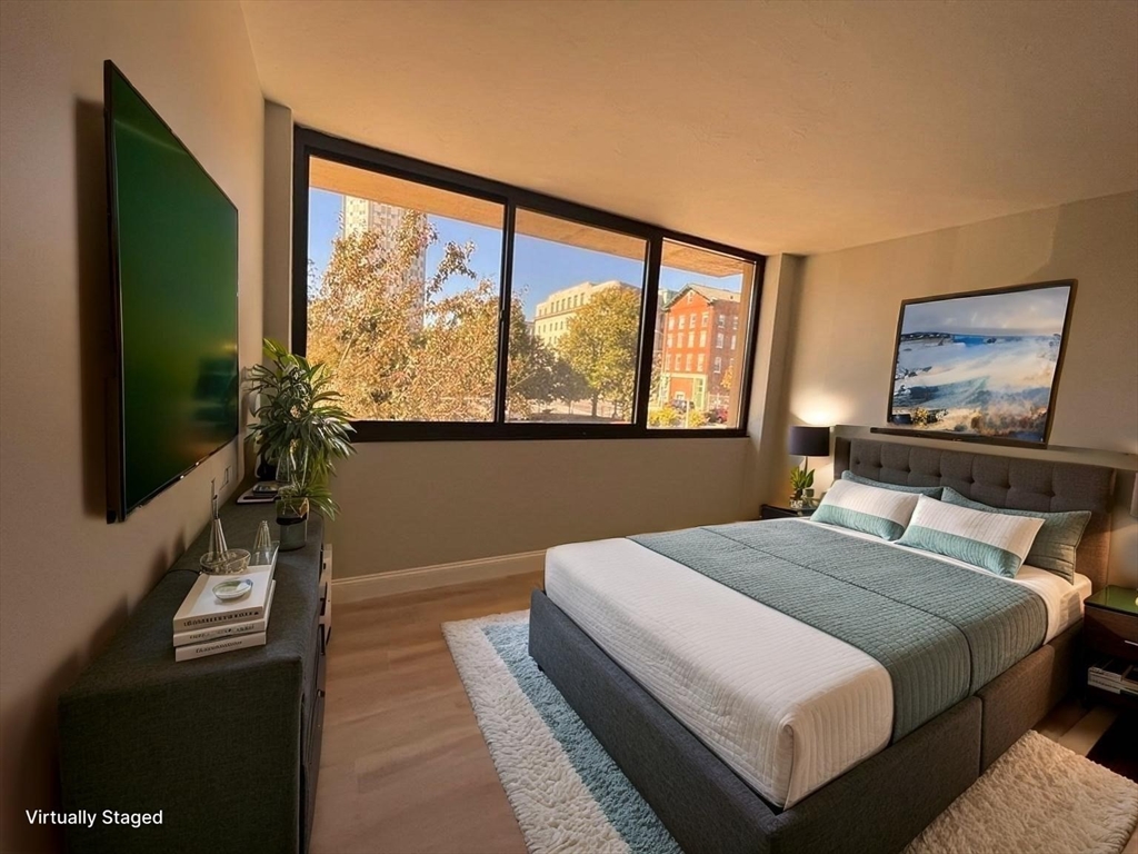 70 Southbridge Street, Unit 215 Worcester, MA 01608 - Photo 17 of 27 a bedroom with a large bed and a flat tv screen on dresser