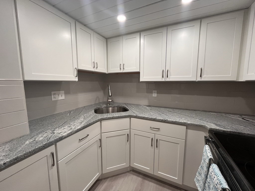 70 Southbridge Street, Unit 215 Worcester, MA 01608 - Photo 7 of 27 a kitchen with granite countertop white cabinets and a sink