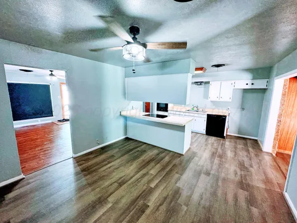a room with stainless steel appliances kitchen island a wooden floor and ceiling fan