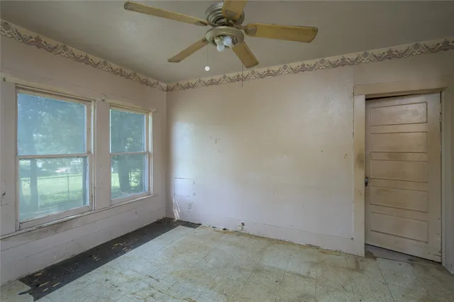 an empty room with windows and fan