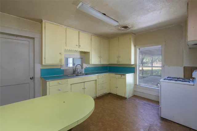 a kitchen with a stove two sinks a refrigerator and cabinets