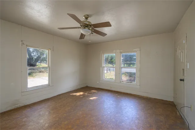 a view of an empty room with a window and wooden floor