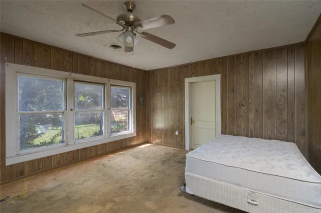 a bedroom with a large bed and a chandelier fan