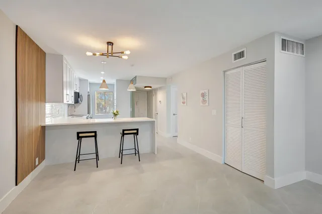 a large white kitchen with a refrigerator a sink dishwasher a dining table and chairs
