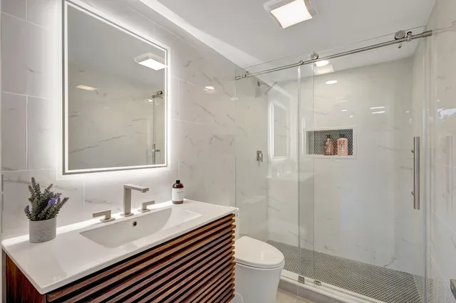 a bathroom with a sink toilet a mirror and shower